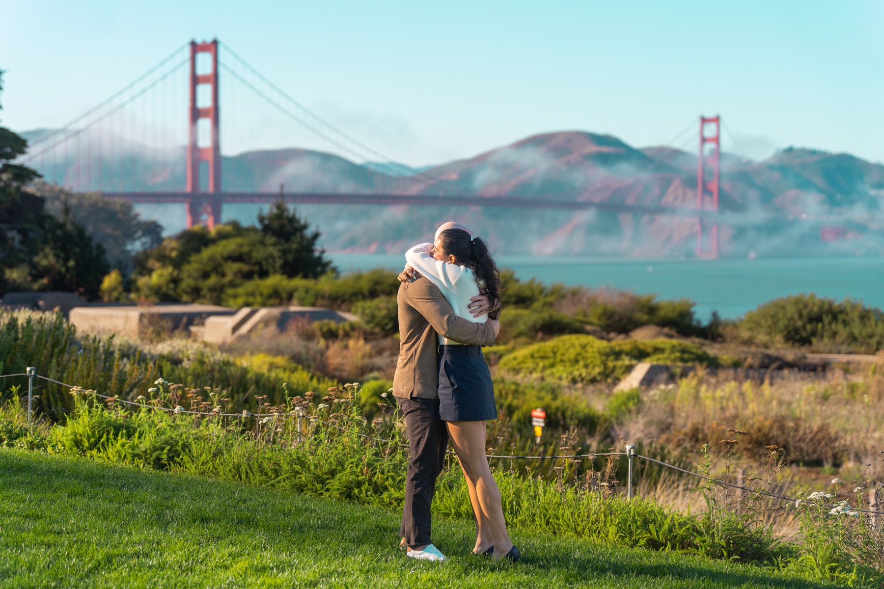 Alex and Abby embracing in a portrait with the Golden Gate Bridge behind them