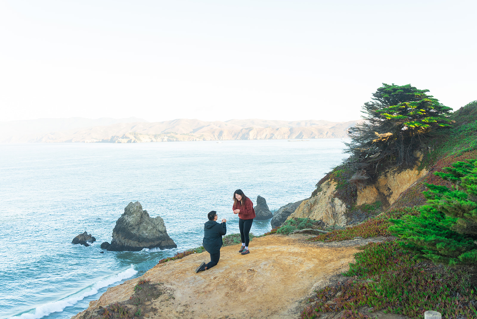 Couple celebrating a surprise proposal at Lands End in San Francisco