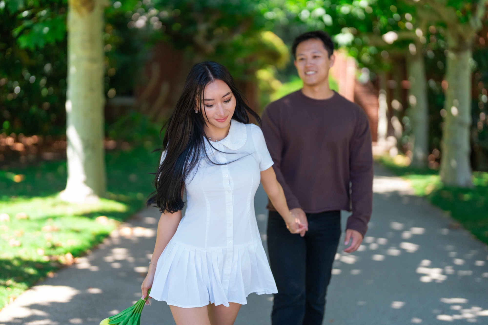 Alexandra leading Ernest along a shaded path at Filoli after their proposal