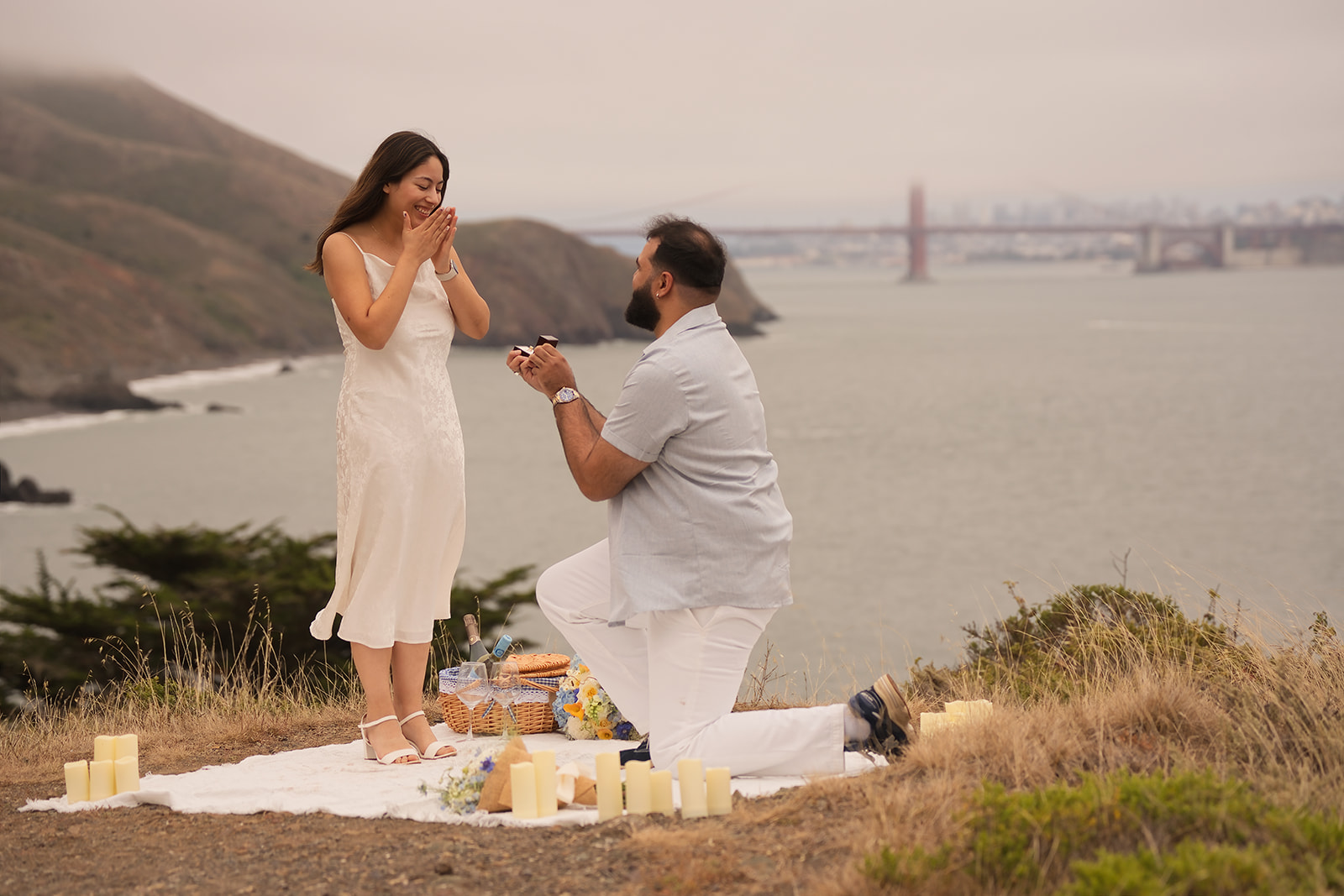 A couple celebrating their surprise proposal with the Golden Gate Bridge in the background